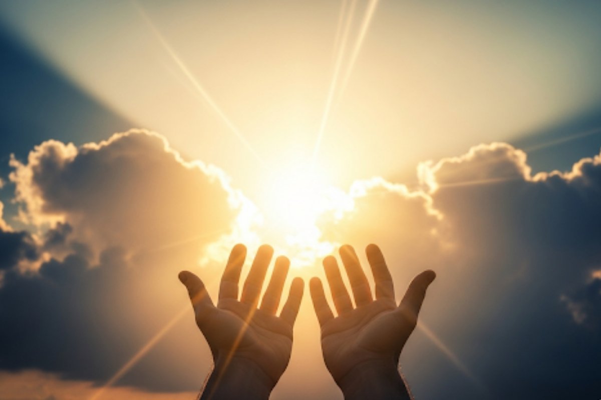 Foto realista de mãos orando, levantadas para o céu, com raios de sol e luz dourada descendo das nuvens, simbolizando a bênção e a provisão divina em finanças.
